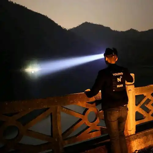 男子晚上爬山用超亮的手电筒照亮黑夜