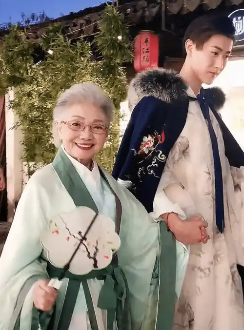 90岁奶奶穿嫩黄大衣好显年轻,被1米9孙子搂着走,回头率超高